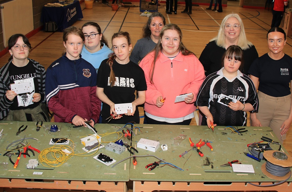 ey stage 4 girls from St Paul’s Bessbrook learn how to wire a plug with tutor Joanne Rea (centre back); Claire King from Women's Tec (second right); and Caitlin Magee from the Housing Executive (right) as part of a special construction day event at Women’s Tec, who are partnering with the Housing Executive to encourage local young people to consider careers in a range of trades.