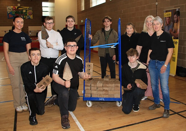 Key Stage 4 DEN Students try their hand at bricklaying, watched by Caitlin Magee, Housing Executive (left); Eimer Shields, St Paul’s Bessbrook (third right); and Claire King and Fiona McMaster from Women’s Tec (second right and far right).