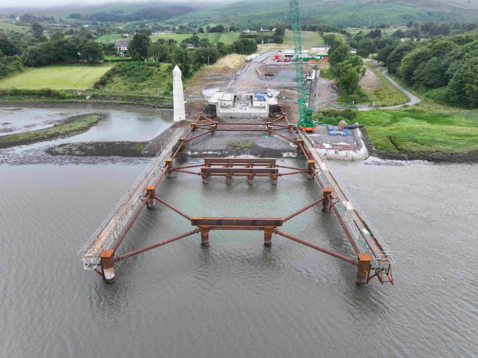 A key milestone has been reached in the construction of the €102 million Narrow Water Bridge, with temporary structures designed by Belfast’s AM Consulting Engineers (AMCE) now extending into the River Newry from both banks. For the first time, passersby can now get a sense of how the long-awaited bridge will eventually span the river, as two new 65m structures extend from each bank into the River Newry. Led by the main contractor BAM Ireland, the work marks a significant engineering achievement on the transformative cross-border infrastructure project connecting Counties Down and Louth