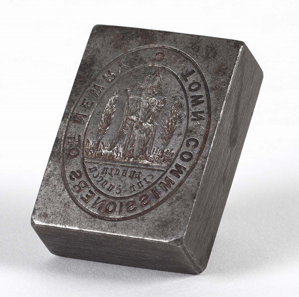 Seal used by the Town Commissioners of Newry, which were established in 1865. The design is based on the seal of the medieval Cistercian abbey at Newry and features a mitred abbot and cross, flanked on either side by a yew tree. Newry & Mourne Museum Collection