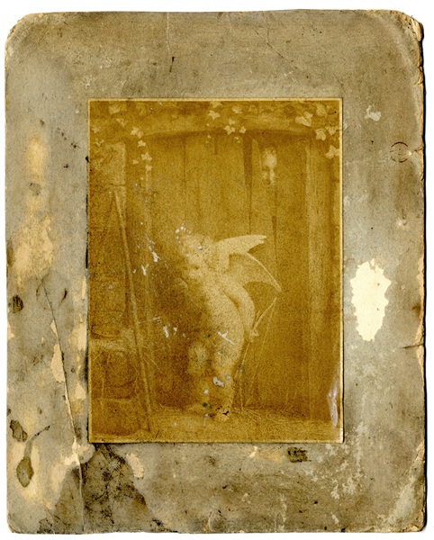 Small Victorian print called ‘Love on a Visit’, of Cupid standing in front of a wooden door, ajar, with a figure looking through it. Newry and Mourne Museum Collection