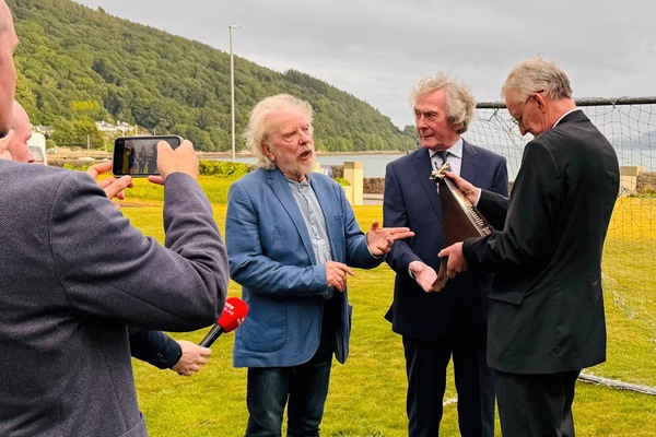 Pat Jennings checks out his award while Hilary Benn MP and Tommy Sands look on.