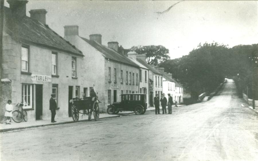 Photograph of Newry Road, Hilltown. Lowry’s taxi can be seen in the image.  Newry and Mourne Museum Collection