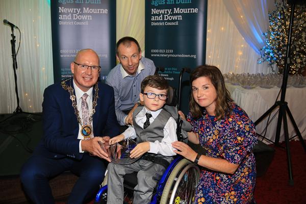 Newry, Mourne and Down District Council Chairperson, Councillor Michael Savage presents Aaron Walsh, who was born with Cerebral palsy and Diplegia in his limbs with a Human Endeavour Civic Award. Aaron had to undergo life changing surgery at St. Louis Children’s Hospice, Missouri and throughout his treatment he has shown remarkable bravery. Included in the picture are his parents Patrick and Lisa Walsh. Newry, Mourne and Down District Council Chairperson, Councillor Michael Savage presents Aaron Walsh, who was born with Cerebral palsy and Diplegia in his limbs with a Human Endeavour Civic Award. Aaron had to undergo life changing surgery at St. Louis Children’s Hospice, Missouri and throughout his treatment he has shown remarkable bravery. Included in the picture are his parents Patrick and Lisa Walsh.