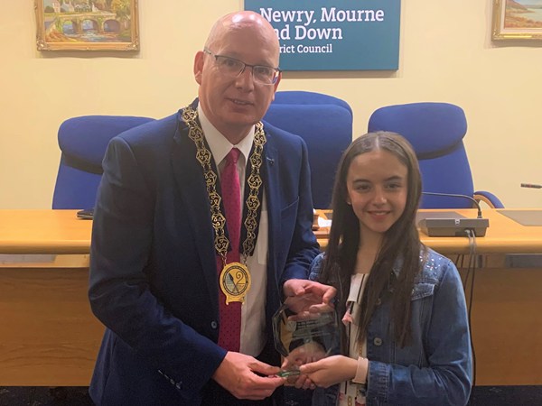 Newry, Mourne and Down District Council Chairperson, Councillor Michael Savage presents Clare Keeley with an inscribed crystal plaque on behalf of the Council to acknowledge  her achievements in the Junior Eurovision Éire 2022 competition. 