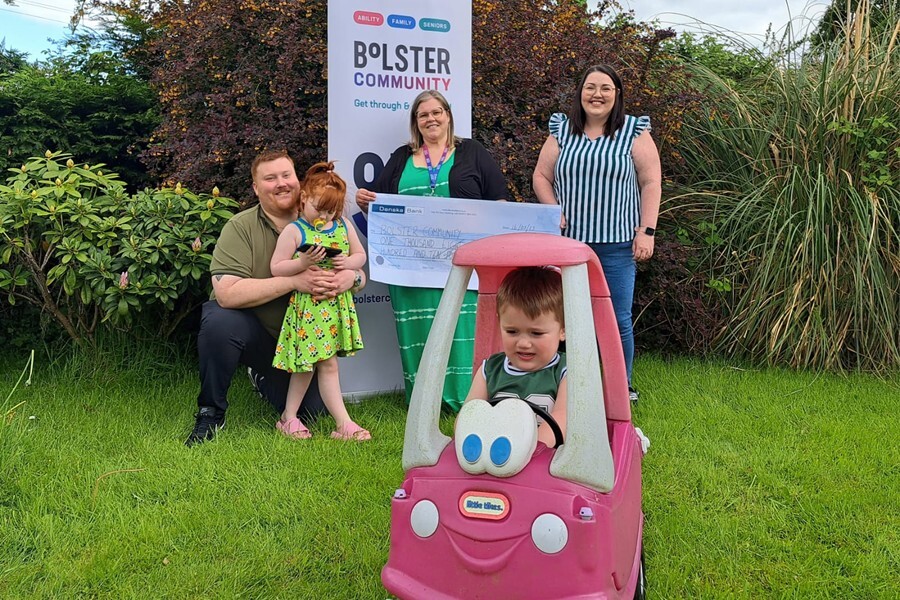 Edel and Sean Devlin, and their children Rosie and Eddie present a cheque to Jena Henning, Support Worker at Bolster Community.  