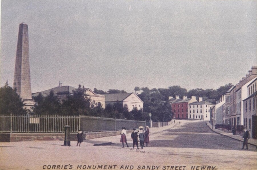 Hand-coloured postcard. In 1895 Thomas Smith described the grounds as a gathering place for nursemaids and children. Shrubs were broken and stones and gravel from the paths scattered over the grass, making mowing difficult. Newry & Mourne Museum Collection