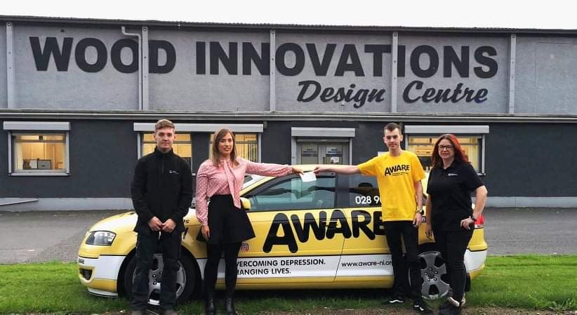 Rachel Mulligan, Conor McKeown & Marie-Louise McKenna of Wood Innovations present Jordan Poucher from AWARE NI with the cheque.