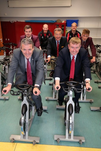 Minister for Social Development, Mervyn Storey, Principal Jarlath Burns (front left) and John Boyd, Chair of IRFU (centre) test out the spinning bikes at the new sports facility at St Paul’s High School, Bessbrook. Photograph: Darren Kidd / Press Eye