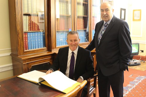 MLA Conor Murphy signing the register in Stormont with Assembly Speaker Mitchel McLaughlin
