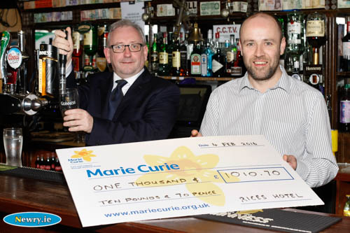Gavin Walsh, Rices Hotel presents the cheque while Michael Hannaway, Newry and Mourne Marie Curie Fundraising Group has a go at pulling a pint. Photograph: Columba O'Hare 