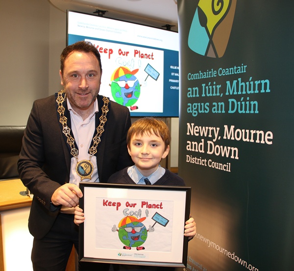 Newry, Mourne and Down District Council Chairperson, Councillor Pete Byrne presenting Junior Section winner Ollie Kearney from St. Malachy’s Primary School, Castlewellan with a framed copy of the winning design which will be displayed as a billboard in Newry and Downpatrick in early 2025.