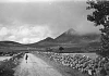Black and white photograph of a school child walking along a road, and stone walls in the Mourne Mountains, 1960s. Newry and Mourne Museum Collection