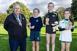Newry, Mourne and Down District Council Chairperson, Councillor Glyn Hanna with the top three finishers in the Individual Girls race. Included are winner Emily Mc Greevy, Glasswater Primary School (centre), runner-up Sophia Murtagh, Ballyholland Primary School (left) and third placed Meabh Murtagh from Carrick Primary School, Burren.