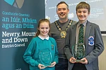 Cllr Phillip Campbell presents the awards to the winners, Charlotte Magee from St Malachy’s Primary School, Camlough and Conor Rooney-Davis, from Kilkeel’s St Louis Grammar School.